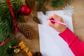 Young woman writes a New Year's greeting card or Christmas wish sheet on a white piece of paper Royalty Free Stock Photo