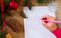 Young woman writes a New Year`s greeting card or Christmas wish sheet on a white piece of paper Royalty Free Stock Photo