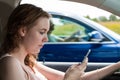 A young woman writes a text message while driving
