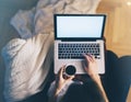 Young woman writes a text message on laptop keyboard with a empty blank screen monitor while having recreation time at home