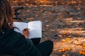 Young woman writing in a diary in an autumn park. Closeup image of a woman writing on a blank notebook. Woman working Royalty Free Stock Photo