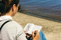 Young woman writing notebook list countries see beach sunny day