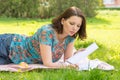 Young woman writing on white paper foxes lying in a meadow in the park