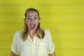 Young woman on a yellow background with surprise expression and excited face