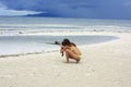 Young woman in yellow bikini takes photographs on the beach