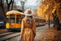 A young woman in yellow clothes in an autumn park looks sadly at a tram pulling away from her. The concept of separation, of being