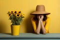 A young woman in yellow clothes on a yellow background in a state of despair and depression near a bouquet of sunflowers