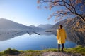 Young woman in yellow coat standing on the coast of Adriatic sea and admiring of stunning winter view of Boka Kotor Bay seascape. Royalty Free Stock Photo