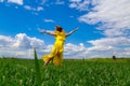 Young woman in yellow dress outdoors in green field. The concept of love of life and openness to the world