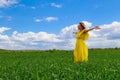 Young woman in yellow dress outdoors in green field. The concept of love of life and openness to the world