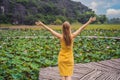 Young woman in a yellow dress on the path among the lotus lake. Mua Cave, Ninh Binh, Vietnam. Vietnam reopens after Royalty Free Stock Photo