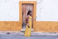 Young woman in yellow dress walking with smart phone and map on the old streets in the city. Portugal. Travel concept Royalty Free Stock Photo