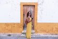 Young woman in yellow dress walking with smart phone on the old streets in the city. Portugal. Travel concept Royalty Free Stock Photo