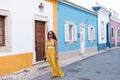 Young woman in yellow dress walking with smart phone on the old streets in the city. Portugal. Travel concept Royalty Free Stock Photo