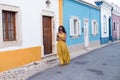 Young woman in yellow dress walking with smart phone on the old streets in the city. Portugal. Travel concept Royalty Free Stock Photo