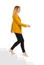 Young Woman In Yellow Jacket And High Heels Is Walking Down The Stairs. Side View Royalty Free Stock Photo