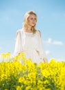 Young woman in yellow oilseed rape field posing in white dress Royalty Free Stock Photo