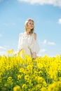 Young woman in yellow oilseed rape field posing in white dress Royalty Free Stock Photo
