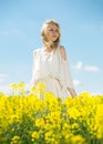 Young woman in yellow oilseed rape field posing in white dress Royalty Free Stock Photo