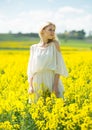 Young woman in yellow oilseed rape field posing in white dress Royalty Free Stock Photo
