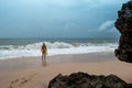 Young woman in yellow rain coat on the beach in heavy rain in Bali