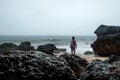 Young woman in yellow rain coat on the beach in heavy rain in Bali