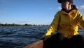 Young woman in yellow raincoat and cap sitting on a boat and looking afield