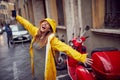 A young woman in a yellow raincoat is excited while walking the city on a rainy day and listening to the music. Walk, rain, city Royalty Free Stock Photo