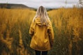 Young woman in yellow raincoat standing in tall grass and looking away Royalty Free Stock Photo