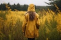 Young woman in yellow raincoat standing in tall grass and looking away Royalty Free Stock Photo