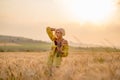 Young woman in yellow among rural field with golden oat field on sunset background Royalty Free Stock Photo