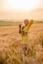 Young woman in yellow among rural field with golden oat field on sunset background Royalty Free Stock Photo