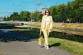 Young woman in a yellow suit and sunglasses is walking around the city. Business image and calm atmosphere. Breathe