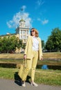 Young woman in a yellow suit and sunglasses is walking around the city. Business image and calm atmosphere. Breathe