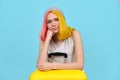 Young woman with yellow suitcase, smiling hipster teenager girl with colored hair