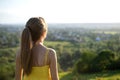Young woman in yellow summer dress standing in green meadow enjoying sunset view Royalty Free Stock Photo