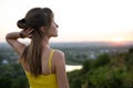 Young woman in yellow summer dress standing in green meadow enjoying sunset view Royalty Free Stock Photo