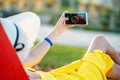 Young woman in yellow summer dress taking selfie with her mobile phone resting on a bench in park Royalty Free Stock Photo