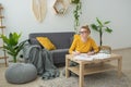 Young woman in a yellow sweater draws and thinking in the room