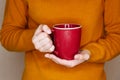 Young woman in yellow sweater is holding red cup of tea or coffee Royalty Free Stock Photo