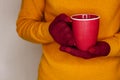 Young woman in yellow sweater is holding red cup of tea or coffee Royalty Free Stock Photo