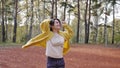 A young woman in a yellow sweater walks in the autumn park. brunette woman jumping and dancing in the forest. Romantic