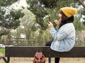 Young woman with yellow woolen cap sitting on a bench painting her lips in front of a mirror Royalty Free Stock Photo