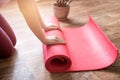 Young woman with yoga mat indoors, fitness healthy and sport concept. Woman rolling her Yoga mat after a workout Royalty Free Stock Photo