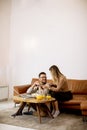 Young woman and young man using laptop for online payment while sitting by sofa at home Royalty Free Stock Photo