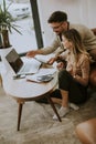 Young woman and young man using laptop while sitting by sofa at home Royalty Free Stock Photo