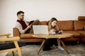 Young woman and young man using laptop while sitting by sofa at home Royalty Free Stock Photo