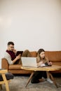 Young woman and young man using laptop while sitting by sofa at home Royalty Free Stock Photo