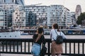 Young women admiring the view of the city at dusk from Thames riverside in London Bridge, London, UK