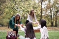 Young women arriving to a picnic, bringing food and drink to their friends